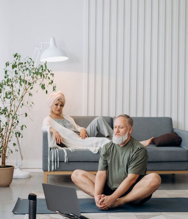 Person smiling while looking at a laptop, ready to start an online exercise session at home.